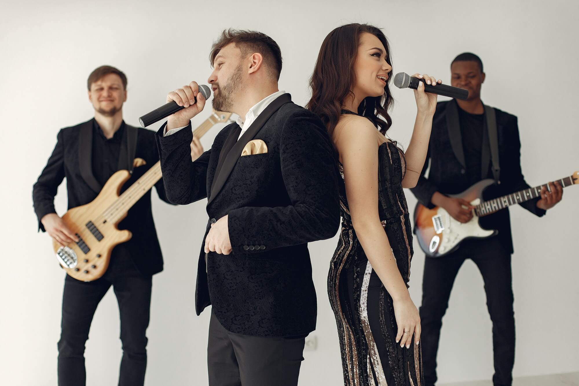 A band in wedding attire performing a song with two singers standing back to back