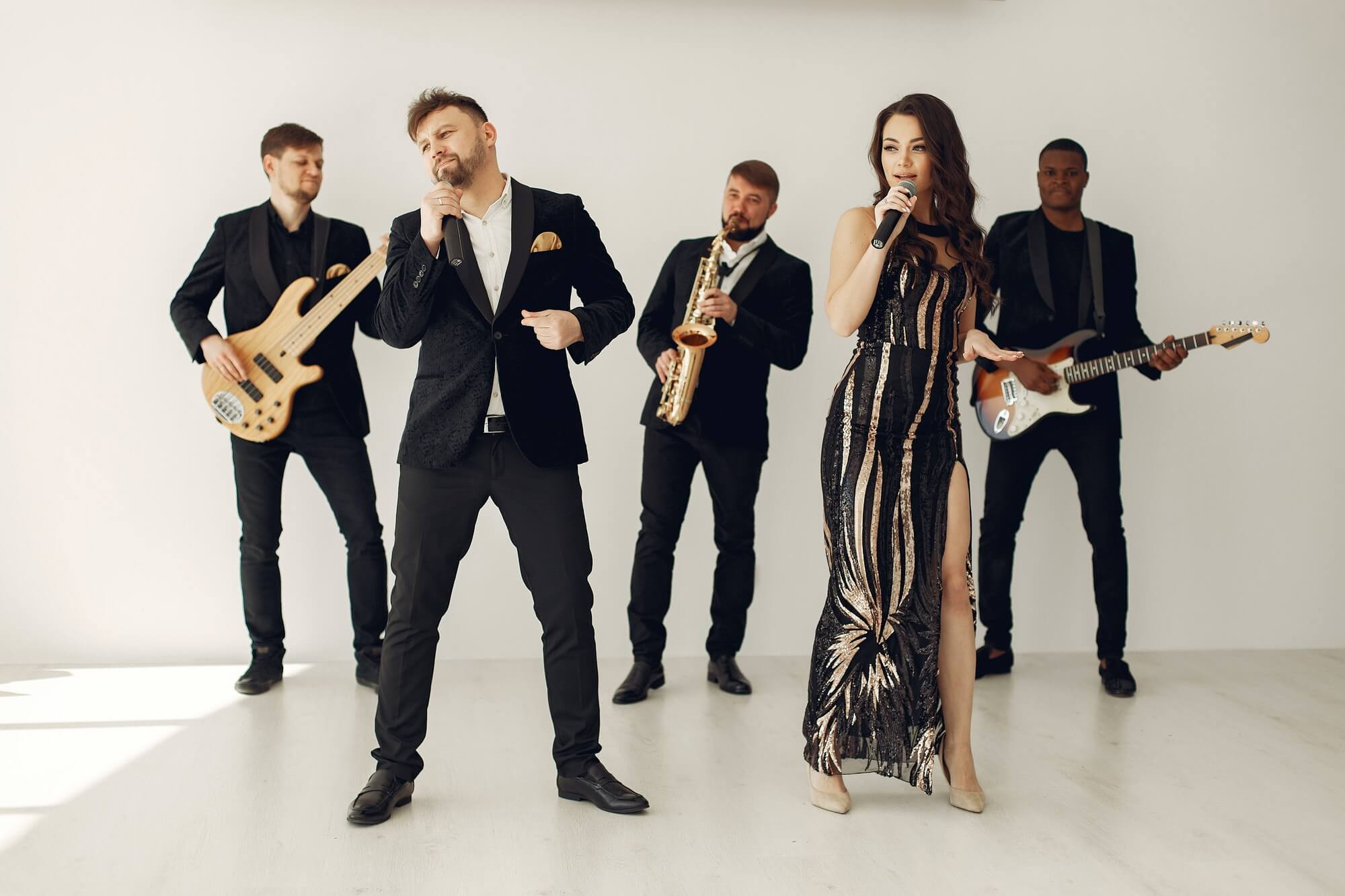 A band in wedding attire performing a song with two singers looking into the distance